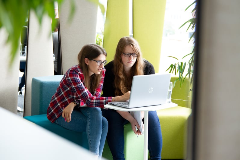 Zwei Kolleginnen arbeiten gemeinsam in der MEINRAD-Worklounge am Laptop
